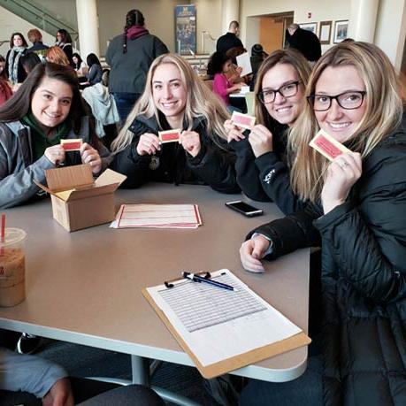 Group of young women sitting at table showing their volunteer cards 